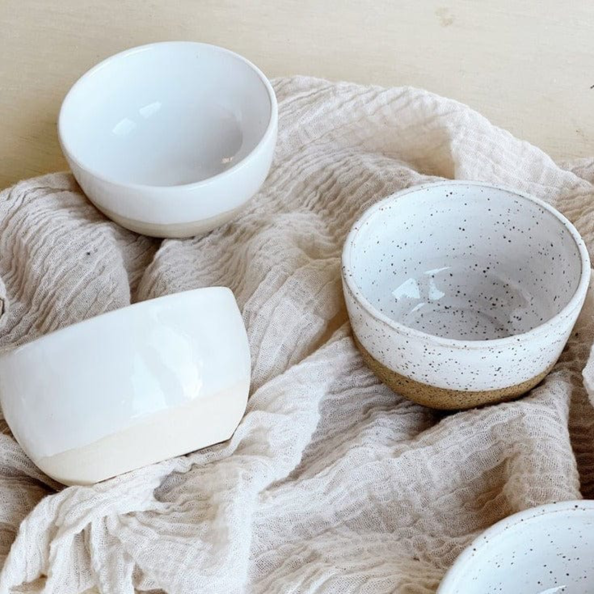 Three ceramic bowls on a textured fabric surface